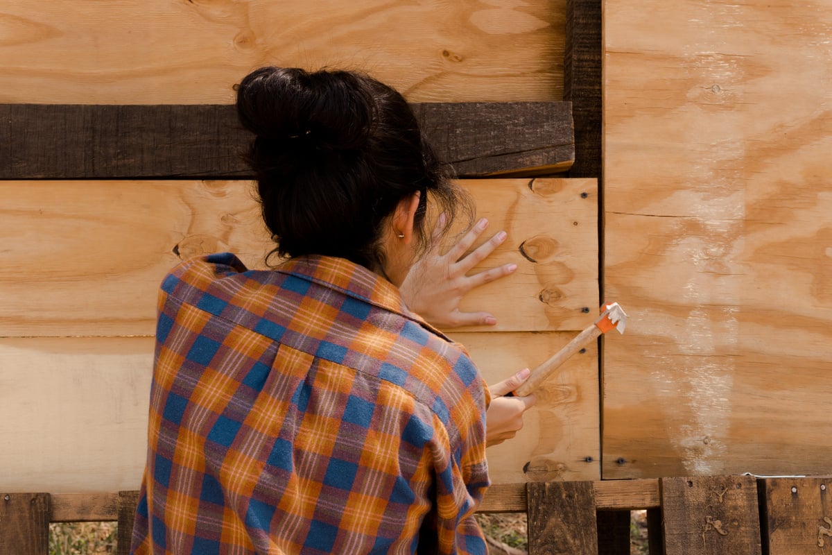 Handywoman hammering Wood Planks 